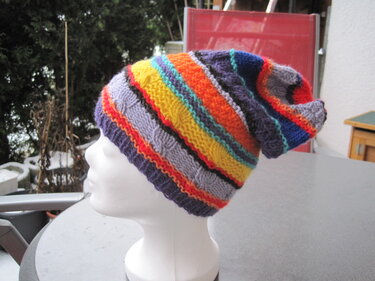 Gestrickte mehrfarbige Slouch‑Mütze mit Rippenbund auf weißer Schaufensterpuppe