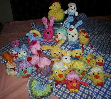 Viele gehäkelte Osterfiguren – Hasen, Küken und Enten – auf blau-weiß kariertem Stoff