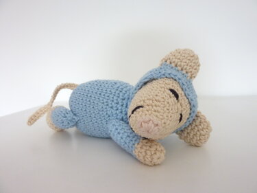 Gehäkelte Amigurumi-Maus liegend in Beige und Hellblau