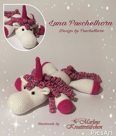 Gehäkeltes Amigurumi‑Einhorn in Weiß mit pinker Mähne, Schweif, Horn und Hufen auf hellem Hintergrund