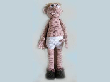 Crocheted amigurumi base doll, neutral tones, white shorts, dark shoes