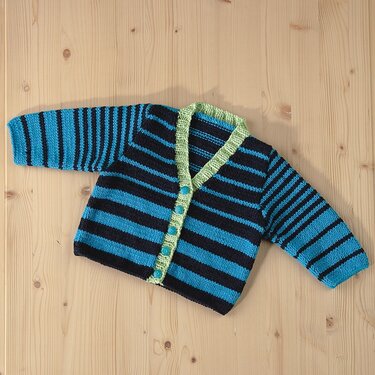 Gestrickte Babyjacke in Türkis und Dunkelblau mit hellgrüner Blende und Knopfleiste, auf hellem Holzuntergrund