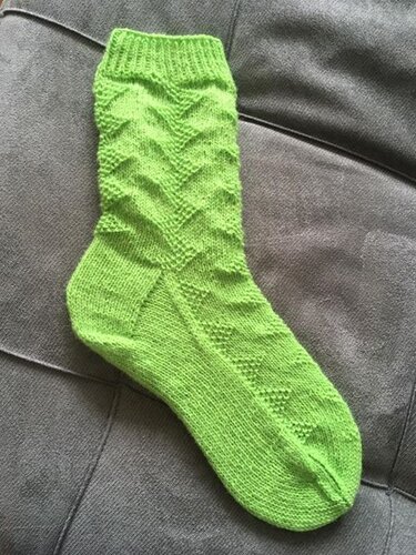 Leuchtend grüne handgestrickte Damensocke mit Chevronmuster auf Stoff