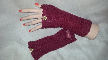 Bordeauxfarbene gestrickte Armstulpen mit Metallblütenanhänger auf Mannequinhand