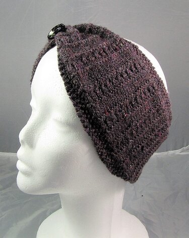 Dunkelbraun-violettes gestricktes Stirnband mit schwarzem Knopf auf Schaufensterpuppe seitlich