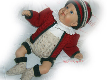 Nahaufnahme einer Babypuppe im farblich abgestimmten gestrickten Strickset mit Jacke, Höschen, Mütze und Socken.