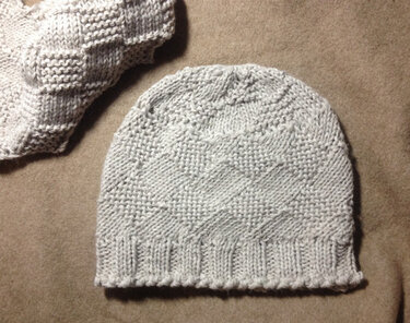 Hellgraue gestrickte Damenmütze mit Rautenstruktur und Rippbündchen auf neutralem Untergrund