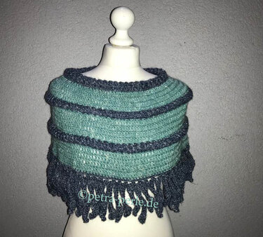 Gehäkelter Damenponcho in Türkis und Grau mit Streifen und Fransen auf einer Schaufensterpuppe.