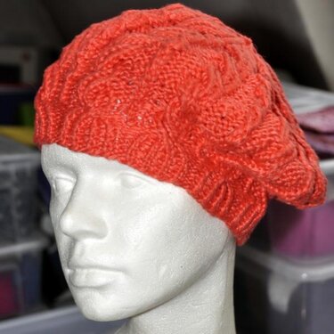 Korallfarbene gestrickte Damenmütze mit Strukturmuster auf Styroporkopf