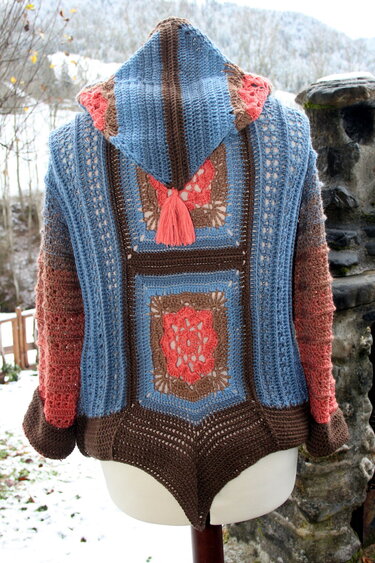 Rückansicht einer gehäkelten Kapuzenjacke mit Granny-Square-Einsätzen, Kapuze und dekorativer Quaste