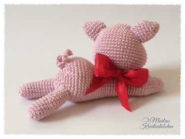 Rosa gehäkeltes Schweinchen mit roter Schleife, liegend, Rückansicht