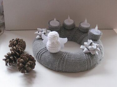 Gestrickter grauer Adventskranz mit vier Teelichtern, weißem Engel, silbernen Schleifen und Tannenzapfen