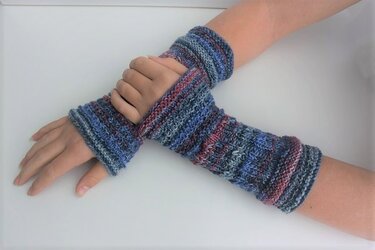 Gestrickte, melierte fingerlose Handschuhe an Händen