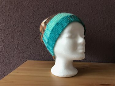 Gestrickte Damenmütze mit Streifen in Türkis, Blau und Braun auf weißem Styroporkopf