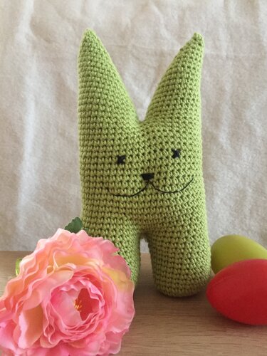 Kompakter gehäkelter Hase in Grün mit Blüte und Ostereiern