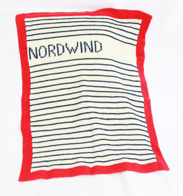 Gestrickte Babydecke creme mit marineblauen Streifen, rotem Rand und NORDWIND Schriftzug