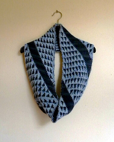 Gestrickter Loop-Schal in Hell- und Dunkelblau mit geometrischem Rautenmuster an einem Kleiderbügel