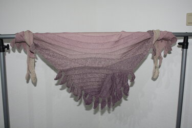 Gestricktes Dreieckstuch in Rosa- bis Violettverlauf mit gezackter Kante, aufgehängt