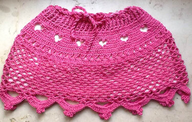 Pink gehäkelter Kinderrock mit Kordelbund, Herzlochmuster und Muschelsaum