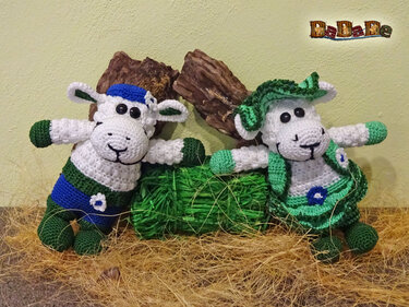 Zwei gehäkelte Amigurumi-Schafe mit Mütze, Kleid und Blumenapplikationen