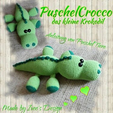 Zwei grüne gehäkelte Amigurumi-Krokodile auf beigem Stoff