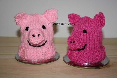 Zwei gestrickte Schweinchen-Eierwärmer in Rosa und Pink auf Eierbechern