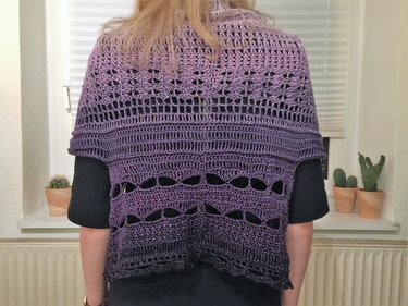 Rückenansicht eines lila gehäkelten Ponchos mit Farbverlauf und Lochmustern