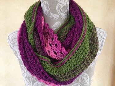 Mehrfarbiger gehäkelter Loop-Schal in Grün, Lila und Pink auf einer Schneiderpuppe.