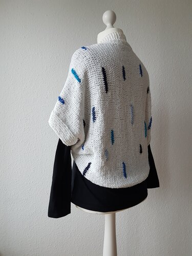 Weißer gestrickter Seelenwärmer mit blauen Einstrickungen an Schaufensterpuppe