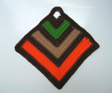 Gehäkelter Topflappen in Rautenform mit orange, hellbraun, grün und braun gestreift und Aufhängeschlaufe