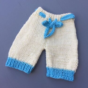 Cremefarbene Strickhose für Babys mit hellblauen Bündchen und Schleife