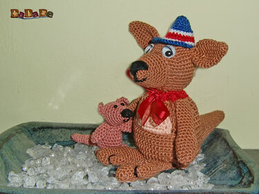 Gehäkeltes Amigurumi-Känguru mit Joey im Beutel, roter Schleife und gestreiftem Minihut