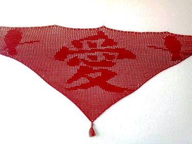 Rotes gehäkeltes Dreieckstuch mit zentralem Schriftzeichen 'Liebe' und Quaste