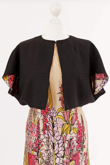 Schwarzer Bolero mit kurzen, weiten Ärmeln über floralem Kleid auf Schaufensterpuppe