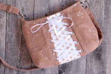 Genähte braune Handtasche mit weißer Schnürung, gepunktetem Einsatz, Stickereien, Pailletten und verstellbarem Trageriemen.