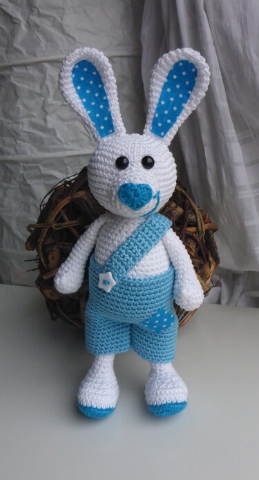 Gehäkelter weißer Hase mit türkiser Latzhose und gepunkteten Ohren
