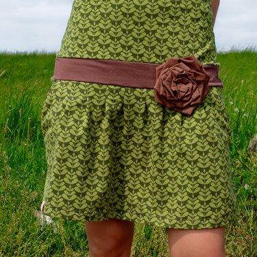 Knielanges grünes Kleid mit Blattmuster, braunem Taillenband und brauner Stoffblüte