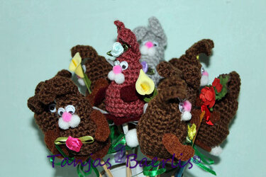 Gehäkelte Amigurumi-Hasen auf Holzstäben mit kleinen Blumen