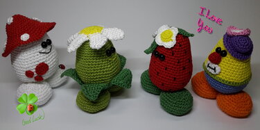 Vier gehäkelte Amigurumi-Glücksbringer: Pilz, Blume, Erdbeere und bunte Figur
