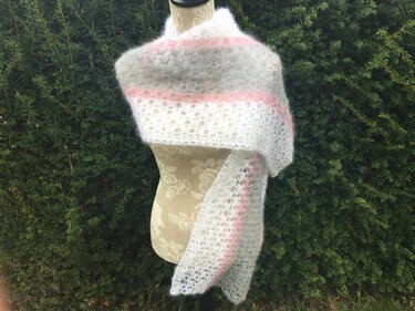 Gehäkelter weißer Schal mit rosa und grauen Streifen auf Schneiderpuppe