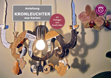 Hängender Kronleuchter aus Karton mit zentraler Glühbirne und dekorativen Papieranhängern