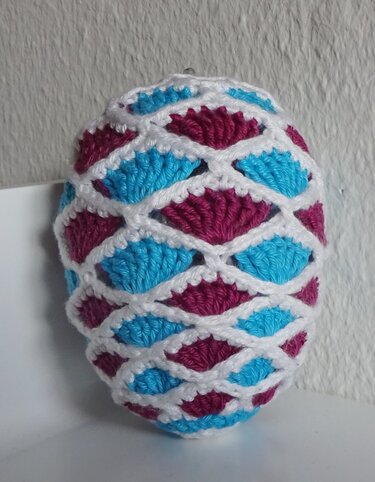Gehäkeltes Osterei mit weißem Gitter und Einsätzen in Türkis und Magenta