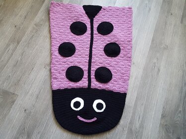 Gehäkelter rosa-schwarzer Babysack im Marienkäfer-Design mit sechs Punkten und Gesicht