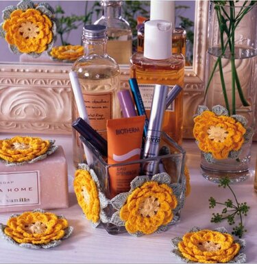 Gehäkelte gelbe Blüten als Untersetzer unter Kosmetikprodukten auf einem hellen Waschtisch