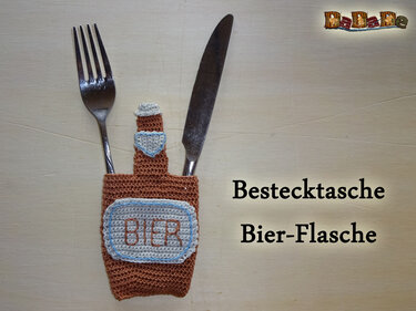 Gehäkelte Bestecktasche in Flaschenform mit besticktem Etikett und eingestecktem Besteck
