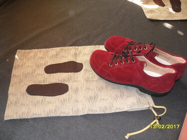 Rote Schnürschuhe neben einem Stoffstück mit zwei braunen, ovalen Zuschnitten.