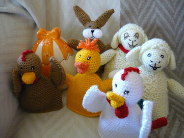 Gehäkelte Figuren: Hase, Lämmer, Hühner und Küken mit Ostereierbecher im Hintergrund.