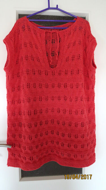 Rotes Stricktop mit Lochmuster und Bindeband am Ausschnitt, aufgehängt an einem Kleiderbügel