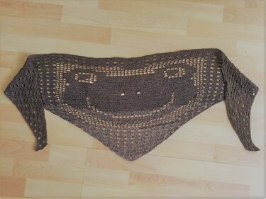 Dreieckiges gehäkeltes Kindertuch in Dunkelgrau mit Smiley-Lochmuster auf hellem Holzboden