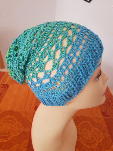 Gehäkelte Slouch-Mütze in Blau-Grün mit offenem Lochmuster auf Mannequin-Kopf